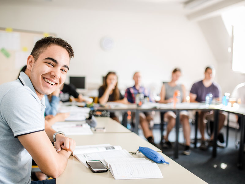 Lächelnder Schüler sitzt im Klassenraum während des Unterrichts