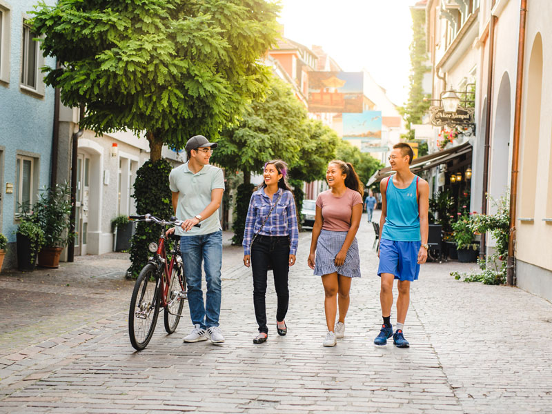 Vier junge Menschen spazieren durch eine gemütliche Altstadtgasse in Radolfzell