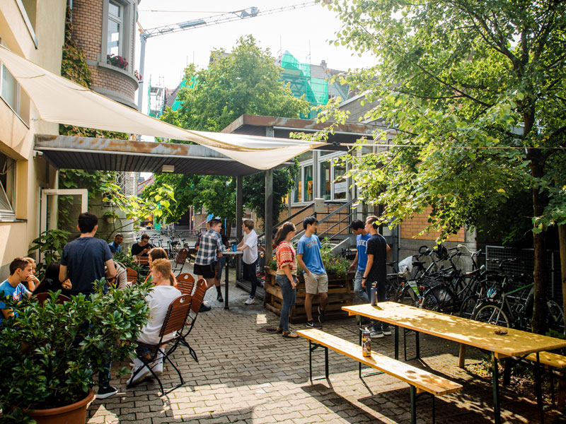 Schülerinnen und Schüler treffen sich im sonnigen Innenhof der Sprachschule