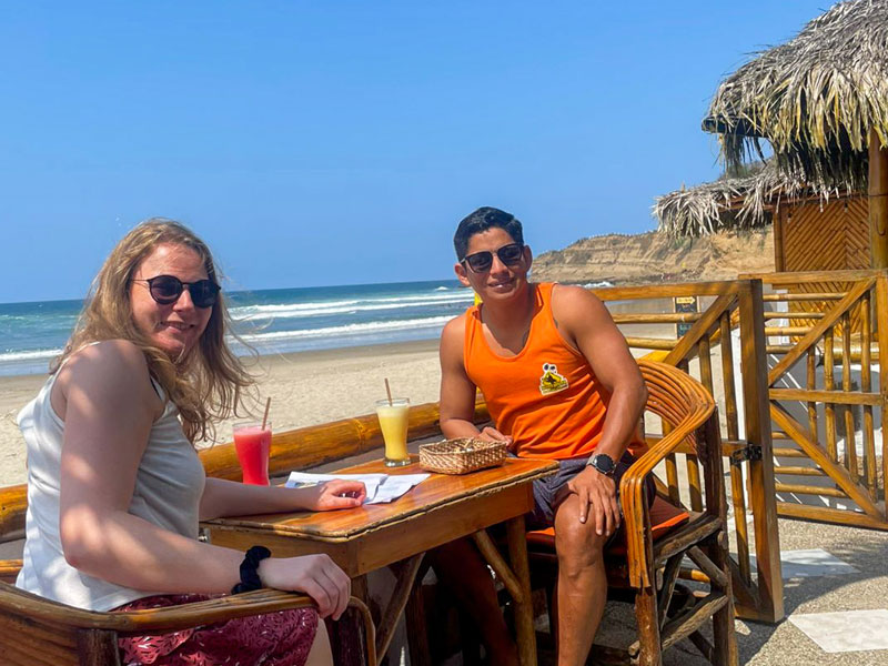 Zwei Personen genießen erfrischende Getränke am Strand von Montañita mit Blick auf das Meer