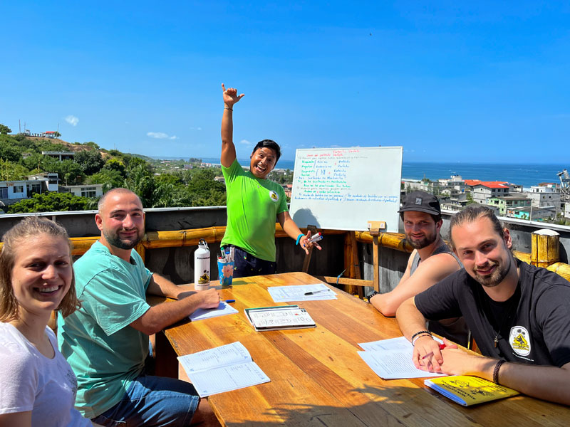 Freundliche Gruppe bei Spanischunterricht im Freien mit Blick auf Montañita und den Pazifik