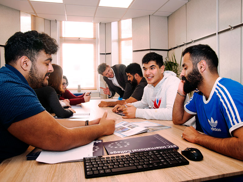 Englischschüler diskutieren lebhaft im Klassenzimmer des ETC International College Bournemouth.