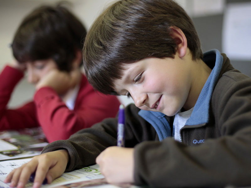 Schüler schreibt konzentriert im Englischkurs an der Sprachschule