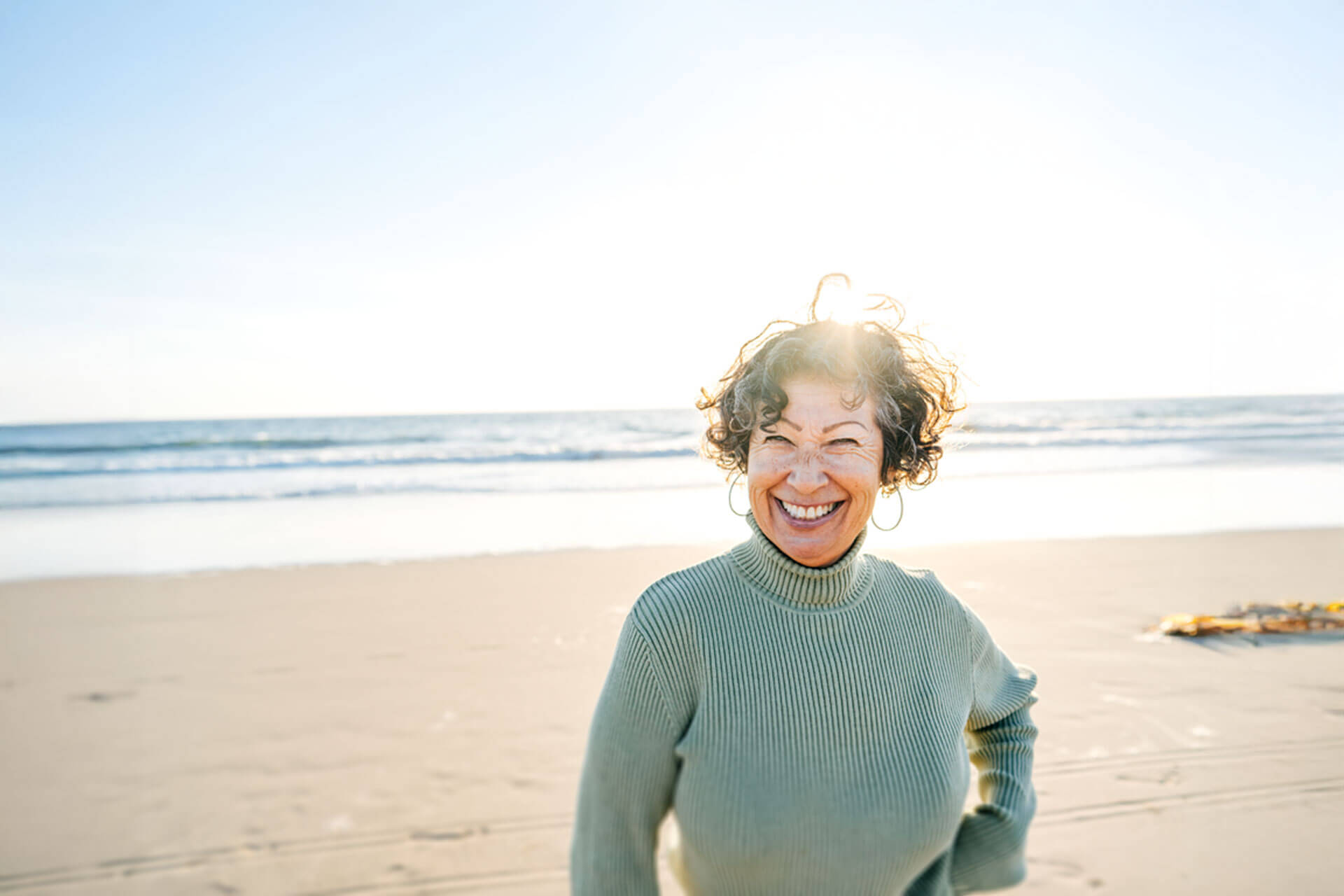 Glückliche Frau am Strand bei Sonnenuntergang – entspannte Atmosphäre am Meer, ideal für Sprachreisen und Auslandsaufenthalte mit Erholung und Lernerlebnis.