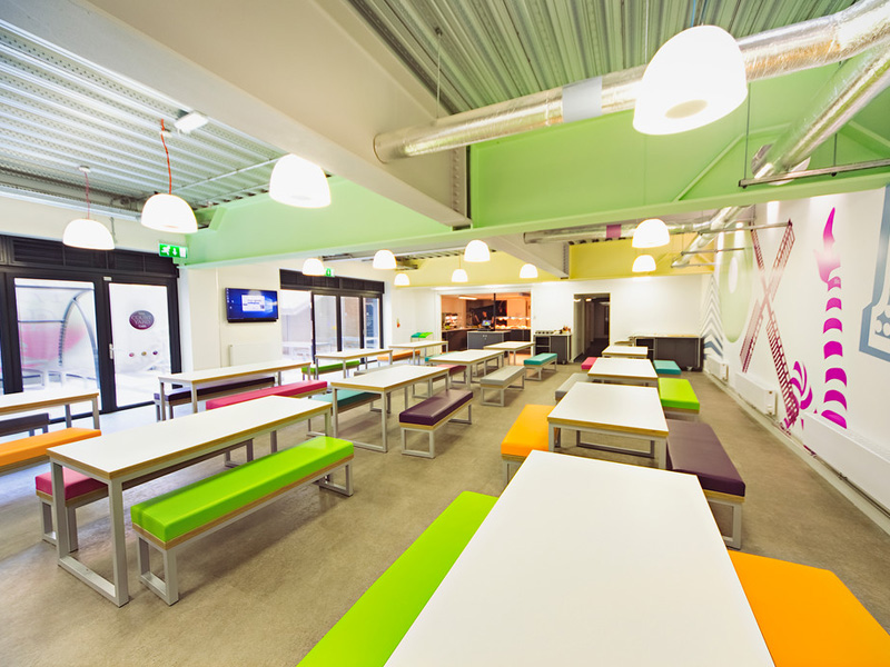 Helle Mensa mit farbenfrohem Design in der Sprachschule