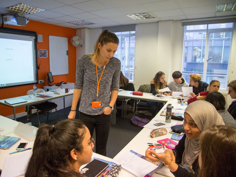 Lehrerin unterstützt Gruppe beim Englisch lernen im Klassenzimmer
