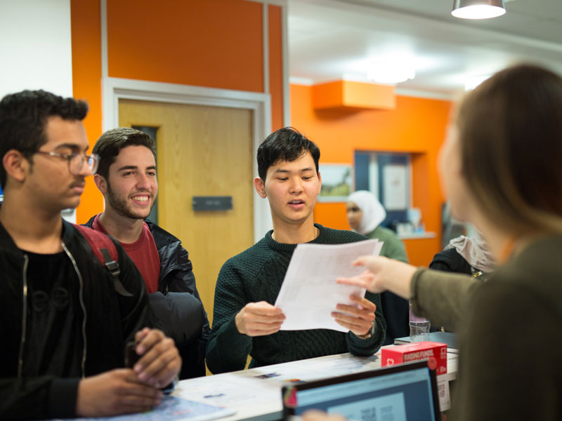 Studierende erhalten Informationen am Empfang der Sprachschule