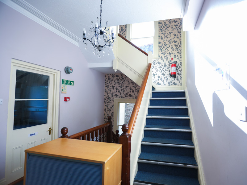 Helles Treppenhaus mit verziertem Geländer und Tapetenmuster in der IH Bristol Sprachschule