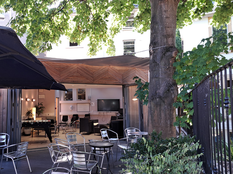 Gemütlicher Innenhof der IH Bristol Sprachschule mit Sitzgelegenheiten unter schattigen Bäumen