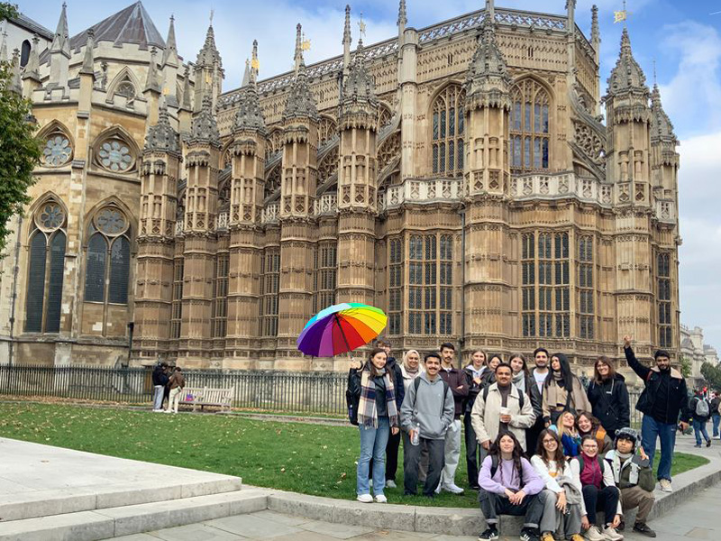 Gruppe internationaler Sprachlernender bei einem Ausflug vor der Westminster Abbey in London