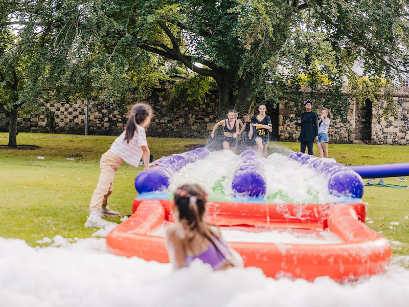 Jugendliche nehmen an einem Outdoor-Spiel mit Wasser und Schaum auf dem Schulgelände teil