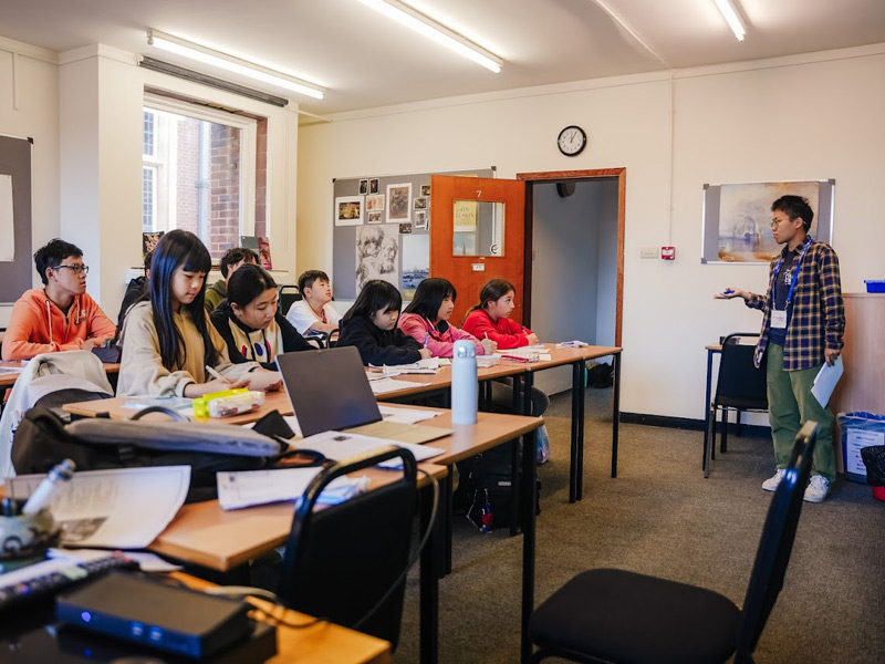 ehrkraft unterrichtet eine Gruppe internationaler Jugendlicher im Klassenzimmer