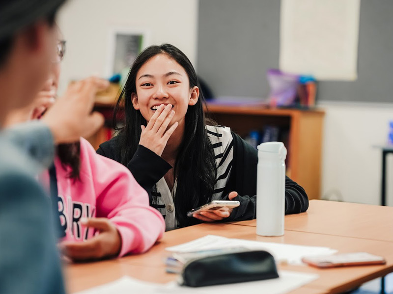 Jugendliche unterhalten sich lachend im Unterricht und genießen die entspannte Lernatmosphäre