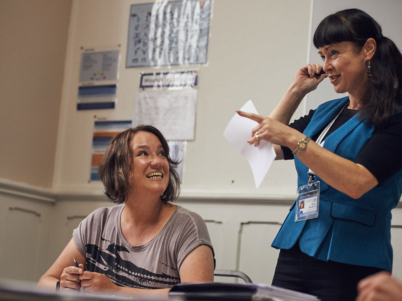 Lehrerin erklärt Teilnehmerin Übungen zur Aussprache im Sprachkurs