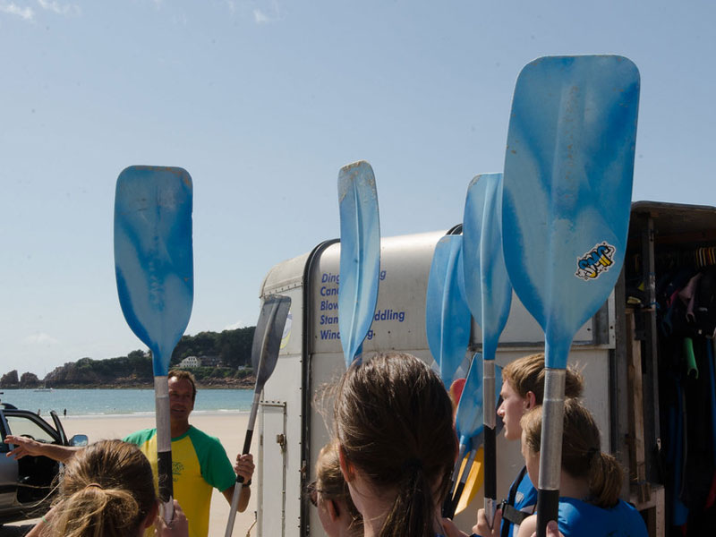 Gruppe junger Sprachschülerinnen und Sprachschüler bereitet sich auf Kajaktour am Strand vor