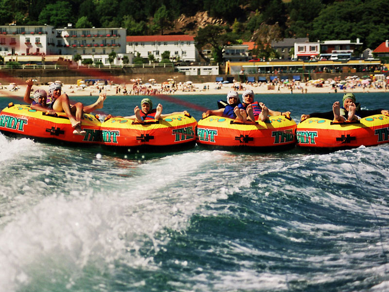 Schülerinnen und Schüler genießen Wassersportaktivität mit aufblasbaren Tubes am Strand von Jersey