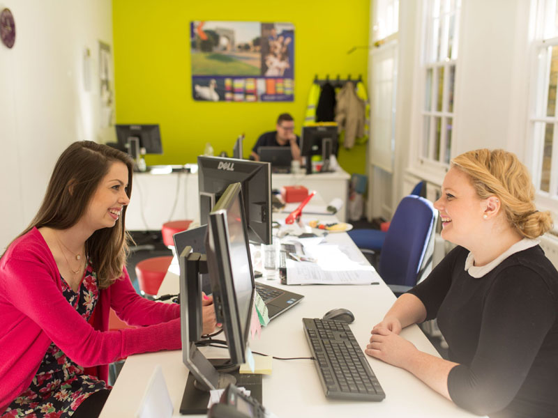 Mitarbeitende beraten Teilnehmende zur Kursorganisation im Sprachkurs