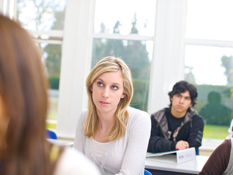 Sprachschüler:innen im Unterrichtsraum mit großen Fenstern und hellem Tageslicht
