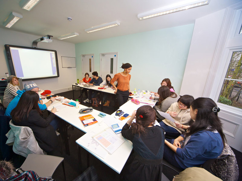 Unterrichtsszene an der Kings London Beckenham, Lehrkraft betreut Lernende in einer internationalen Gruppe