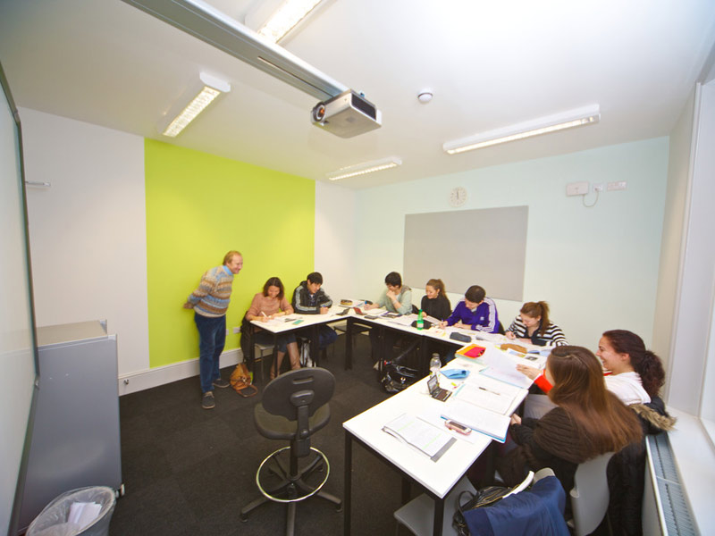 Kleine Lerngruppe arbeitet gemeinsam mit Lehrkraft in einem hellen, modernen Klassenraum