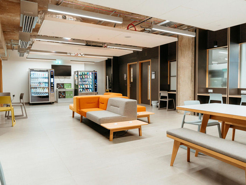 Helle Lounge mit Sitzgelegenheiten und Snackautomaten