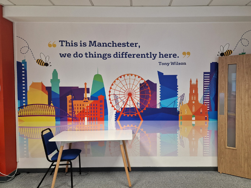 Lernbereich der International House Manchester mit Stadtgrafik und Zitat von Tony Wilson an der Wand