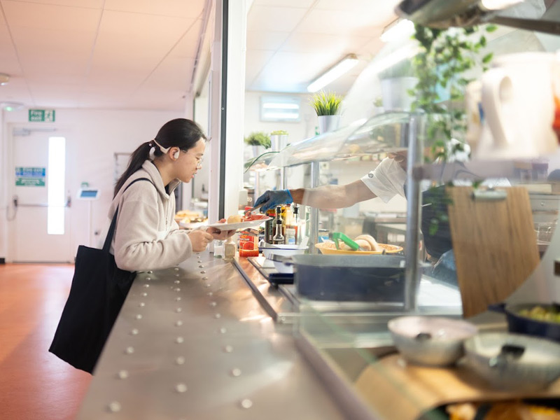 Sprachschülerin holt ihr Mittagessen in der Cafeteria der Sprachschule in Oxford