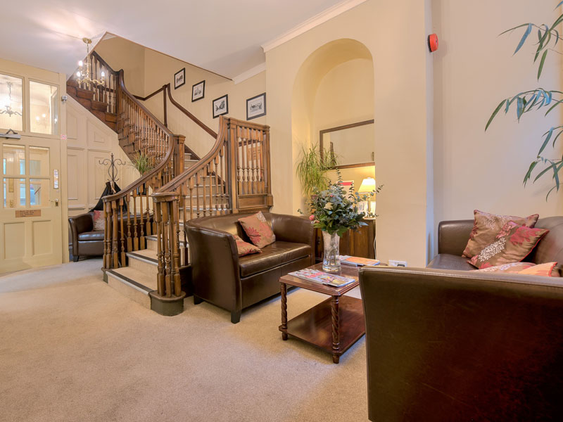 Helle Lobby der Severnvale Academy mit Sitzbereich und Treppenhaus.