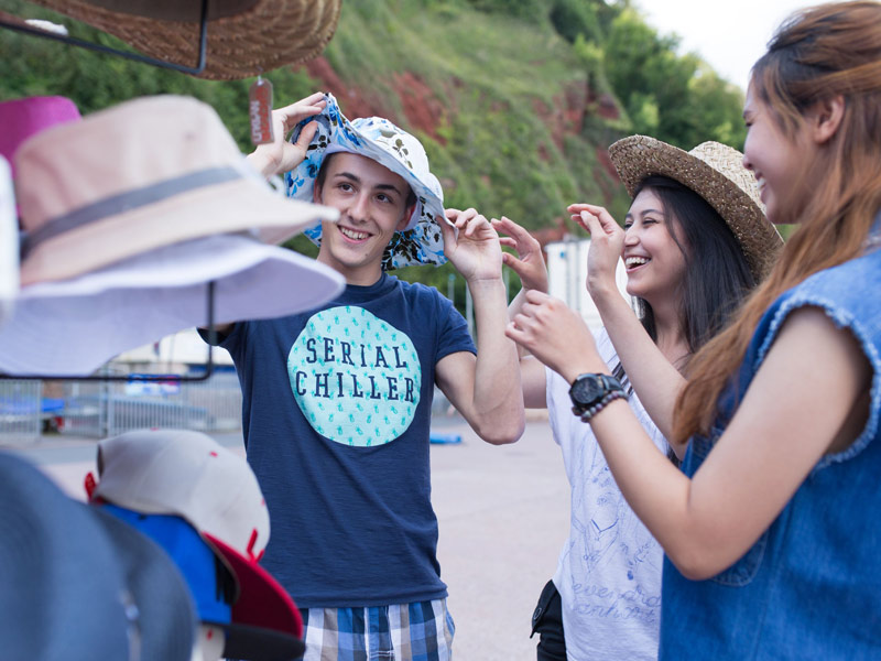 Schüler probieren Hüte auf dem Markt während ihres Sprachaufenthalts