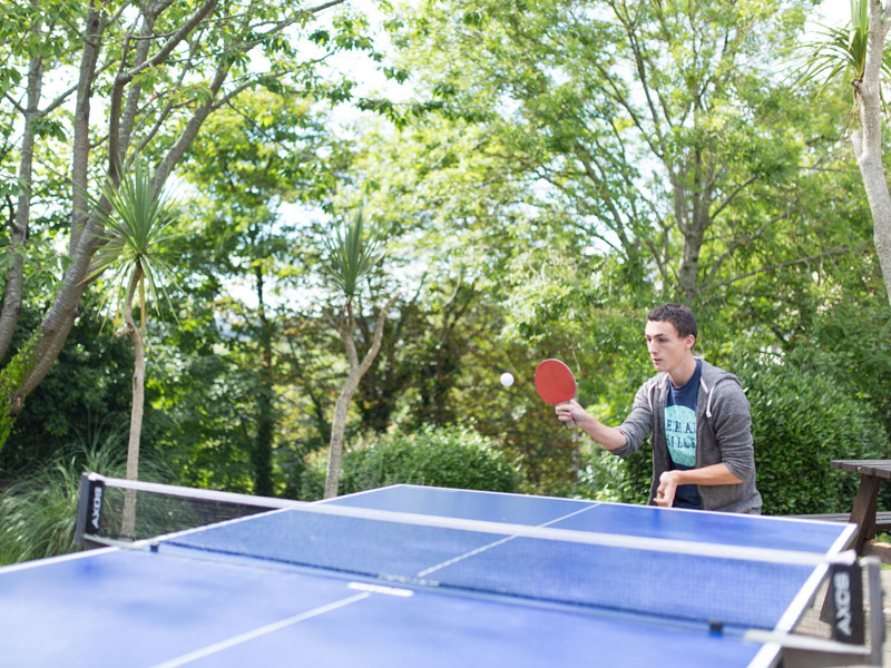 Teilnehmender spielt Tischtennis im Garten der Sprachschule
