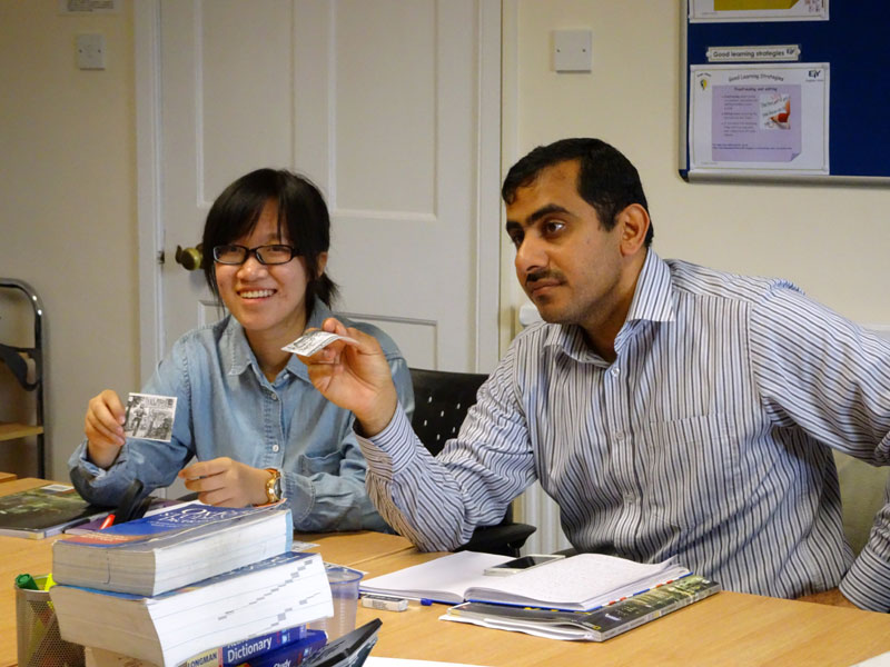 Sprachschüler:innen arbeiten gemeinsam im Unterricht und zeigen Lernmaterialien