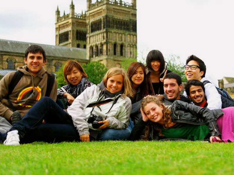 Gruppe internationaler Sprachschüler:innen entspannt gemeinsam auf einer Wiese vor der Kathedrale von York