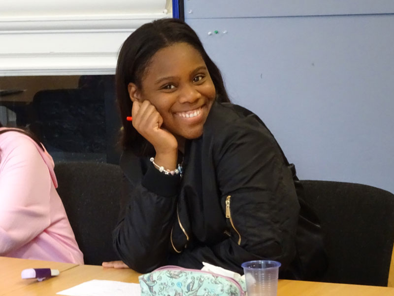 Lachende Sprachschülerin sitzt am Tisch im Klassenraum der English in York Schule
