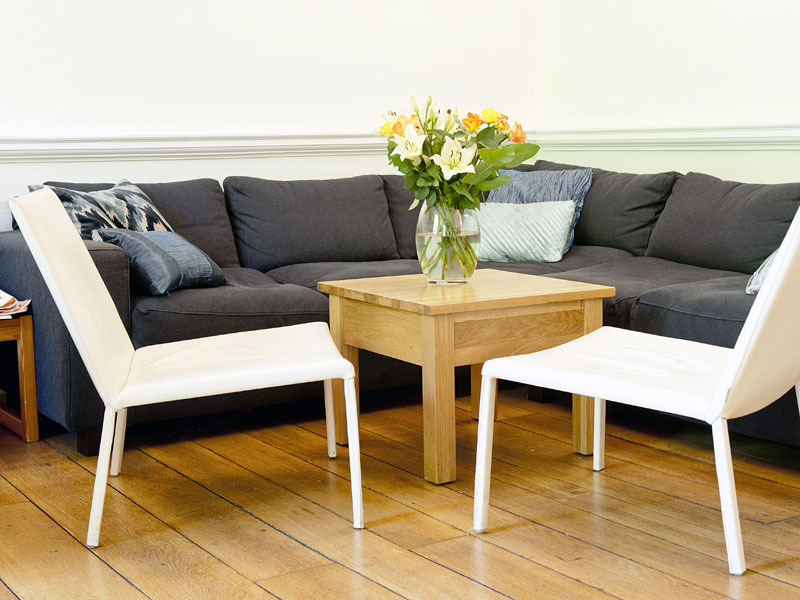 Gemütlicher Aufenthaltsraum mit Sofa, Holzboden und Blumenstrauß bei York Associates