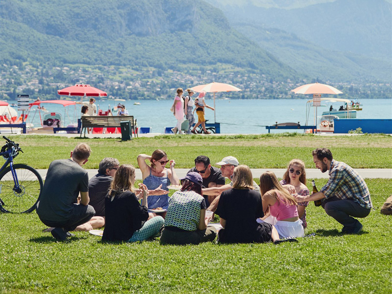 Gruppe von Sprachschülern beim gemeinsamen Lernen am Ufer des Lac d’Annecy