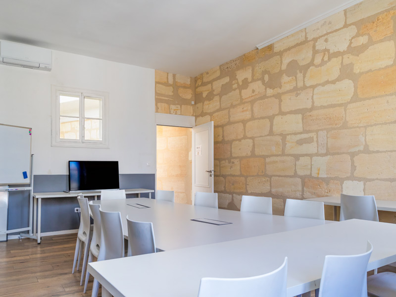 Unterrichtsraum mit Steinwand und Bildschirm – moderner Lernraum für Französisch-Sprachkurse in Bordeaux.