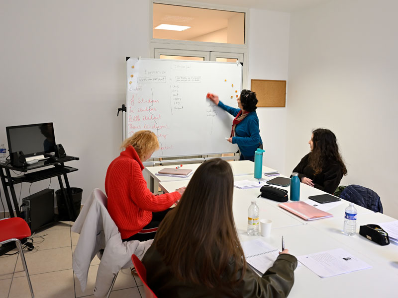 Professeure devant le tableau blanc pendant un cours collectif de français à Nice.