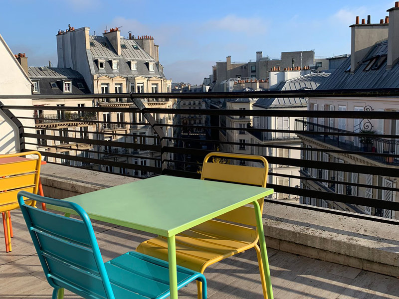 Terrasse mit bunten Tischen und Stühlen an der Les Ateliers FL Sprachschule im Herzen von Paris