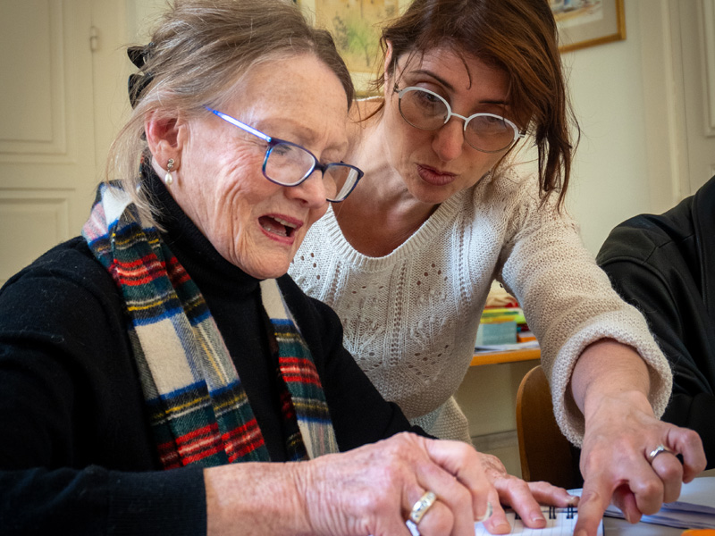 Lehrkraft unterstützt ältere Sprachlernende individuell beim Französischunterricht