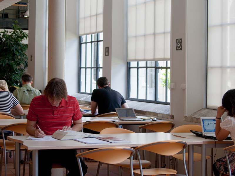Lernende beim konzentrierten Arbeiten im hellen Studienbereich der Cavilam Sprachschule in Vichy