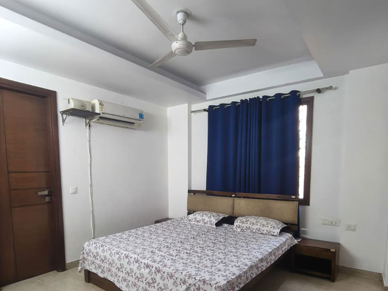 Schlafzimmer im Apartment in Neu-Delhi mit Doppelbett, Klimaanlage und Fenster.