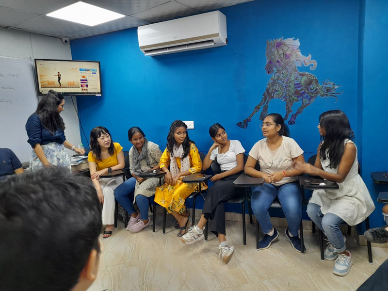 Lernende sitzen in einem Halbkreis im Unterrichtsraum der ILSC Neu-Delhi und unterhalten sich lebhaft