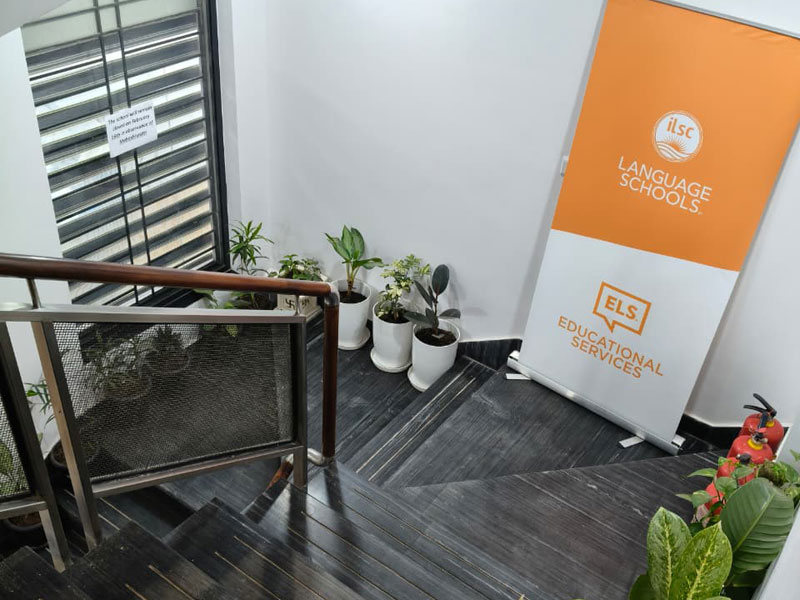 Escalier intérieur de l’école ILSC à New Delhi avec plantes et panneau d’information