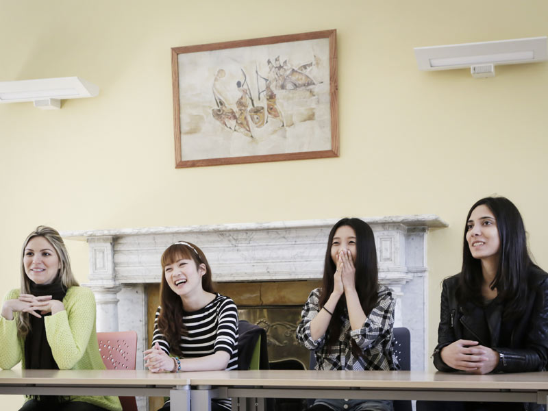 Lachende Sprachschülerinnen beim Englischunterricht in klassischem Raum mit Kamin