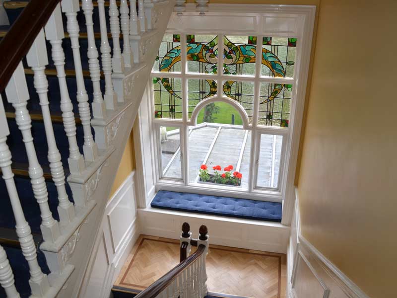 Treppenaufgang der Emerald Sprachschule Dublin mit buntem Glasfenster und Sitznische