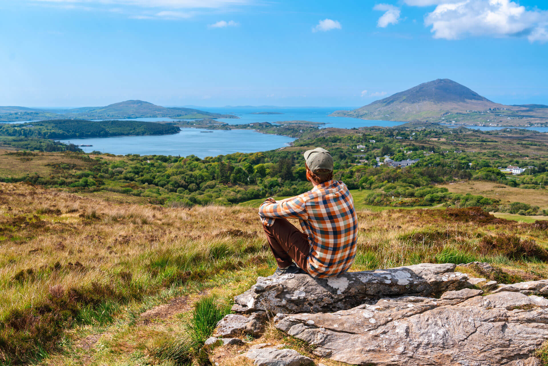 Person mit Blick auf die Küstenlandschaft bei Galway mit Bergen und Meer im Hintergrund