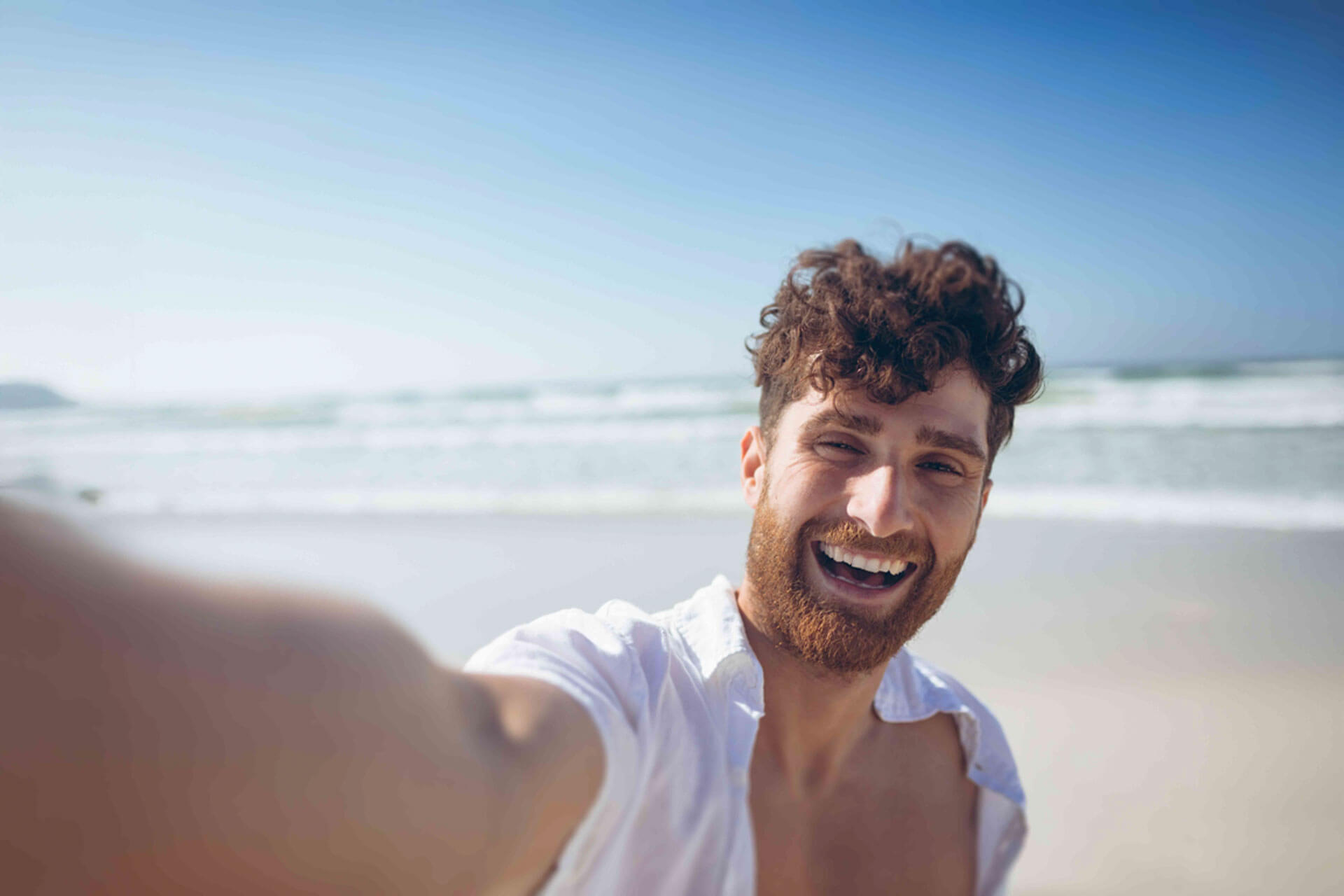 Lachender junger Erwachsener am Strand