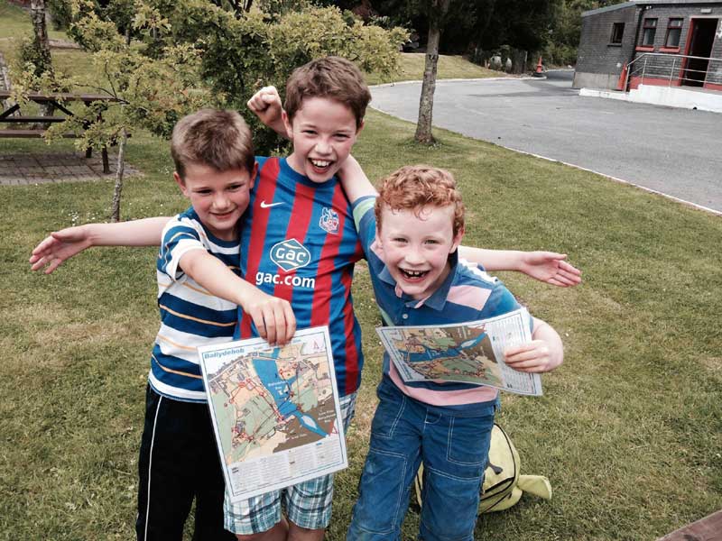 Drei Kinder mit Karten bei einer Outdoor-Aktivität