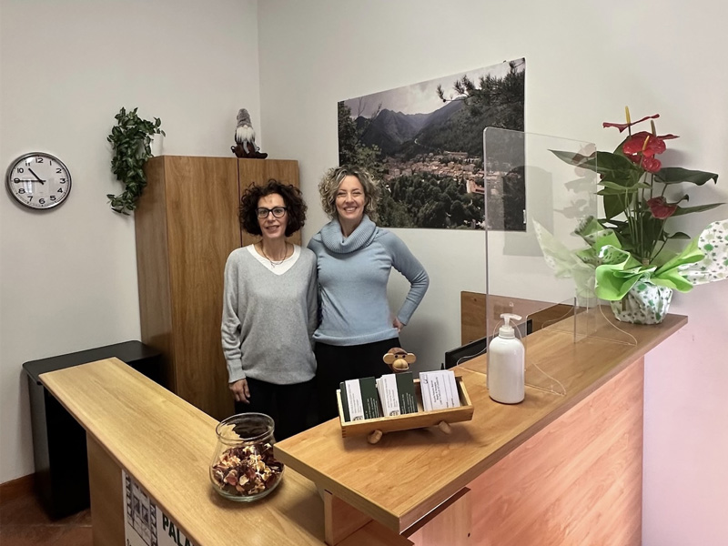 Zwei Mitarbeiterinnen der Scuola Palazzo Malvisi stehen an der Rezeption und begrüßen Gäste