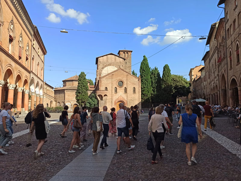 Gruppe von Teilnehmenden erkundet die Piazza Santo Stefano in Bologna bei Sonnenschein